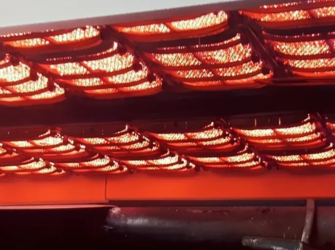 Close-up of industrial infrared emitters glowing red inside a drying unit.