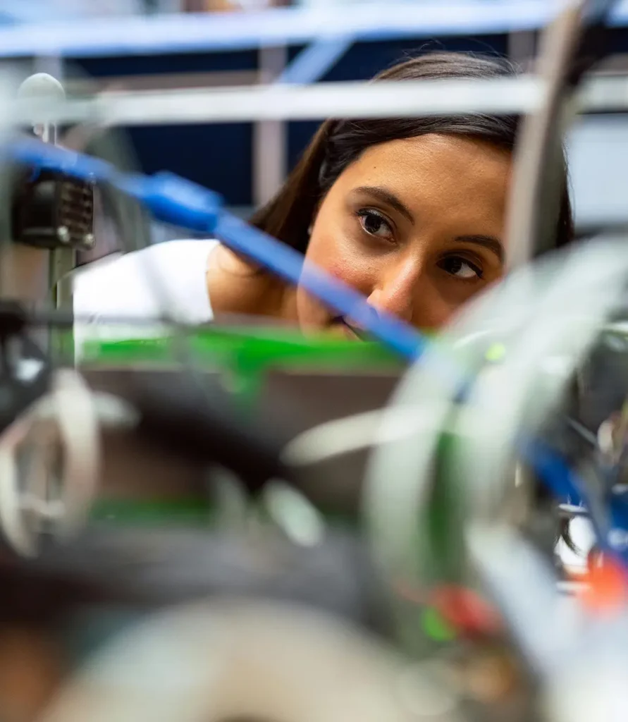 Close-up of a woman examining industrial components through cables.