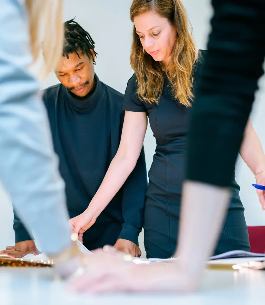 Group of people collaborating over documents at a table in an office setting.